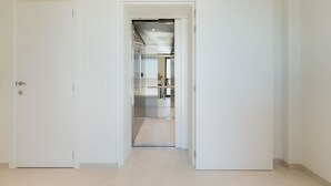 A hallway leading to a kitchen area with a stainless steel range hood and a tripod in the background. - Large apartment with balcony, 3 BR and 2 Bathrooms (Antwerpen)