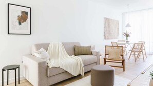 Un soggiorno moderno con divano, poggiapiedi e zona pranzo con sedie e tavolo.
