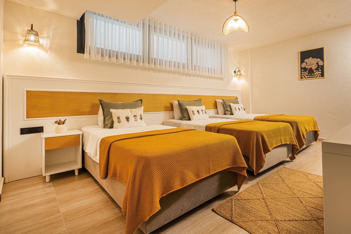 A hotel room with two beds, a small bedside table, a nightstand, a wall-mounted TV, and a ceiling light.