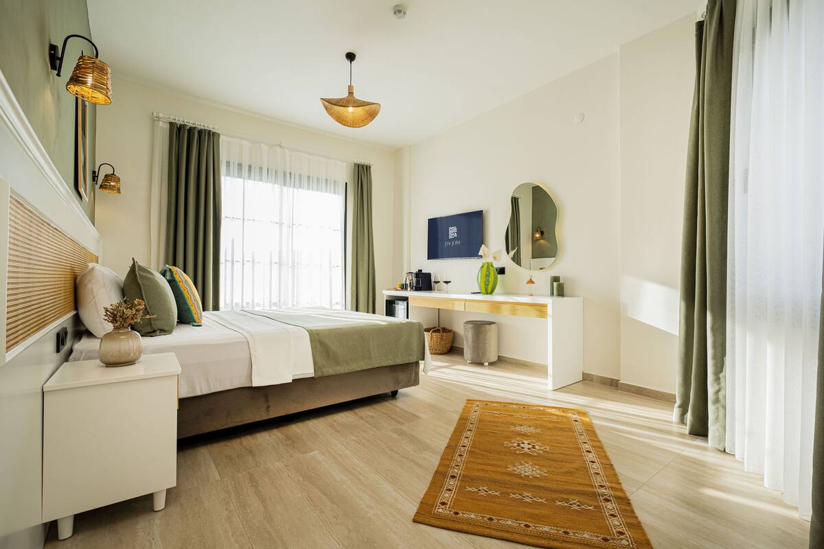 A modern bedroom with a bed, bedside table, lamp, and a desk with a mirror.