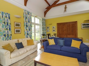 A living room with two sofas, a wooden table, and a large window with curtains.