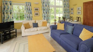 A living room with two sofas, a coffee table, a TV, and framed pictures on the wall. - Ty Cellin (Tregaron)