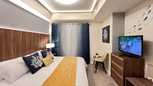 Una habitación de hotel moderna con una cama, televisión, escritorio y una silla.