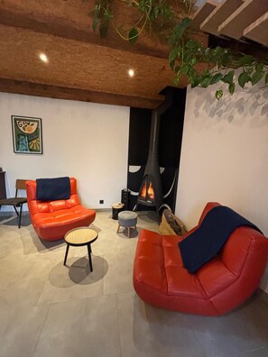 A modern living room with a fireplace, red leather sofas, a small round table, and a wooden ceiling. - Near Béziers unusual house, "LOFT VIGNERON". (Pouzolles)