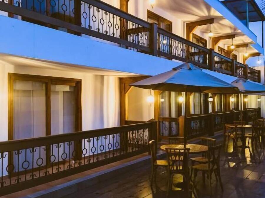 A multi-story building with outdoor seating areas and a balcony with a railing.