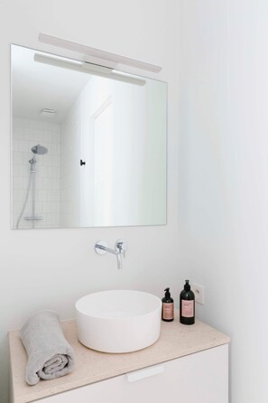 Een badkamer met een wit wastafel, een ronde spiegel en een handdoek.