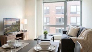 Una sala de estar moderna con televisor, comedor y sofá.