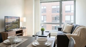 Ein modernes Wohnzimmer mit Fernseher, Esstisch und Sofa.