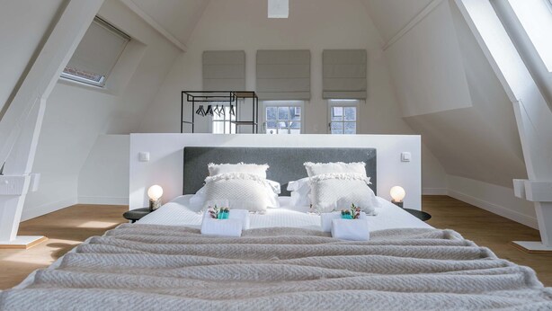 Un dormitorio amplio con una cama grande, un armario y una ventana con persianas.