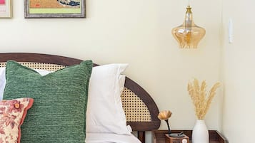 Une chambre à coucher avec un lit, des oreillers, une table de chevet, une radio et un luminaire suspendu.
