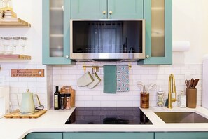 Une cuisine avec des armoires de couleur turquoise, un four à micro-ondes en acier inoxydable et une cuisinière noire.