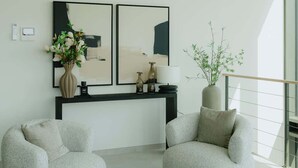 A modern living room with two armchairs, a round coffee table, a console table with decorative items, and abstract paintings on the wall. - Luxurious City Penthouse with Panoramic Terrace (Antwerpen)