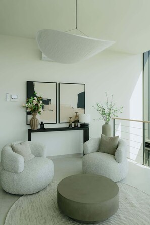 A modern living room with two armchairs, a round coffee table, a console table with decorative items, and abstract paintings on the wall. - Luxurious City Penthouse with Panoramic Terrace (Antwerpen)