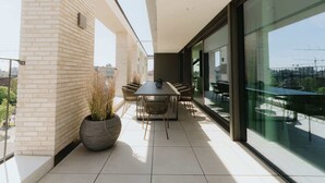 A modern outdoor dining area with a brick wall, a large potted plant, and a table with chairs. - Luxurious City Penthouse with Panoramic Terrace (Antwerpen)