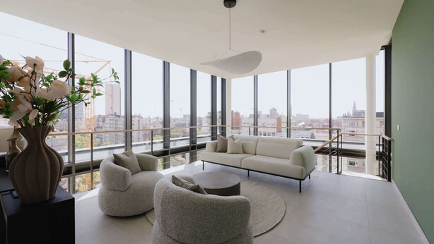 A modern living room with a sofa, two armchairs, and a coffee table, large windows offering a city view, and a vase with flowers on a side table. - Luxurious City Penthouse with Panoramic Terrace (Antwerpen)