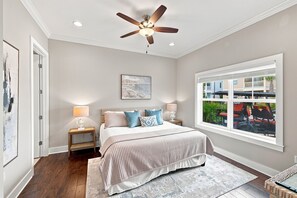 A bedroom with a bed, bedside lamps, a ceiling fan, a window with a view, and a painting on the wall. - Newly Furnished | LSV | Community Pool (Santa Rosa Beach)