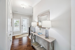 A hallway with a wooden console table, two lamps, a mirror, and a door with white blinds. - Pool, 6-Seater LSV, Bikes and a 5 Min Walk to Beach Access (Santa Rosa Beach)