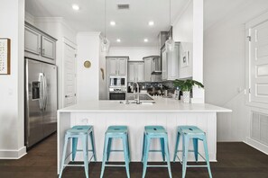 A modern kitchen with a central island, stainless steel appliances, and a white color scheme. - Fitness Facility | Pool Access | Garage (Panama City)