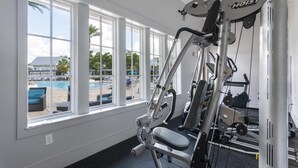 Un gimnasio con vistas a una piscina a través de amplios ventanales.
