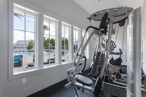 Ein Fitnessraum mit Blick auf ein Schwimmbad durch große Fenster.