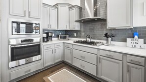 Una cocina moderna con muebles blancos, electrodomésticos de acero inoxidable y un salpicadero de ladrillo.