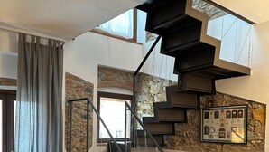 A modern interior with a spiral staircase, a stone wall, and a framed certificate on the wall. - Apartment 'Casa La Corte in Capannori' with Private Pool, Wi-Fi & Air Conditioning (Capannori)
