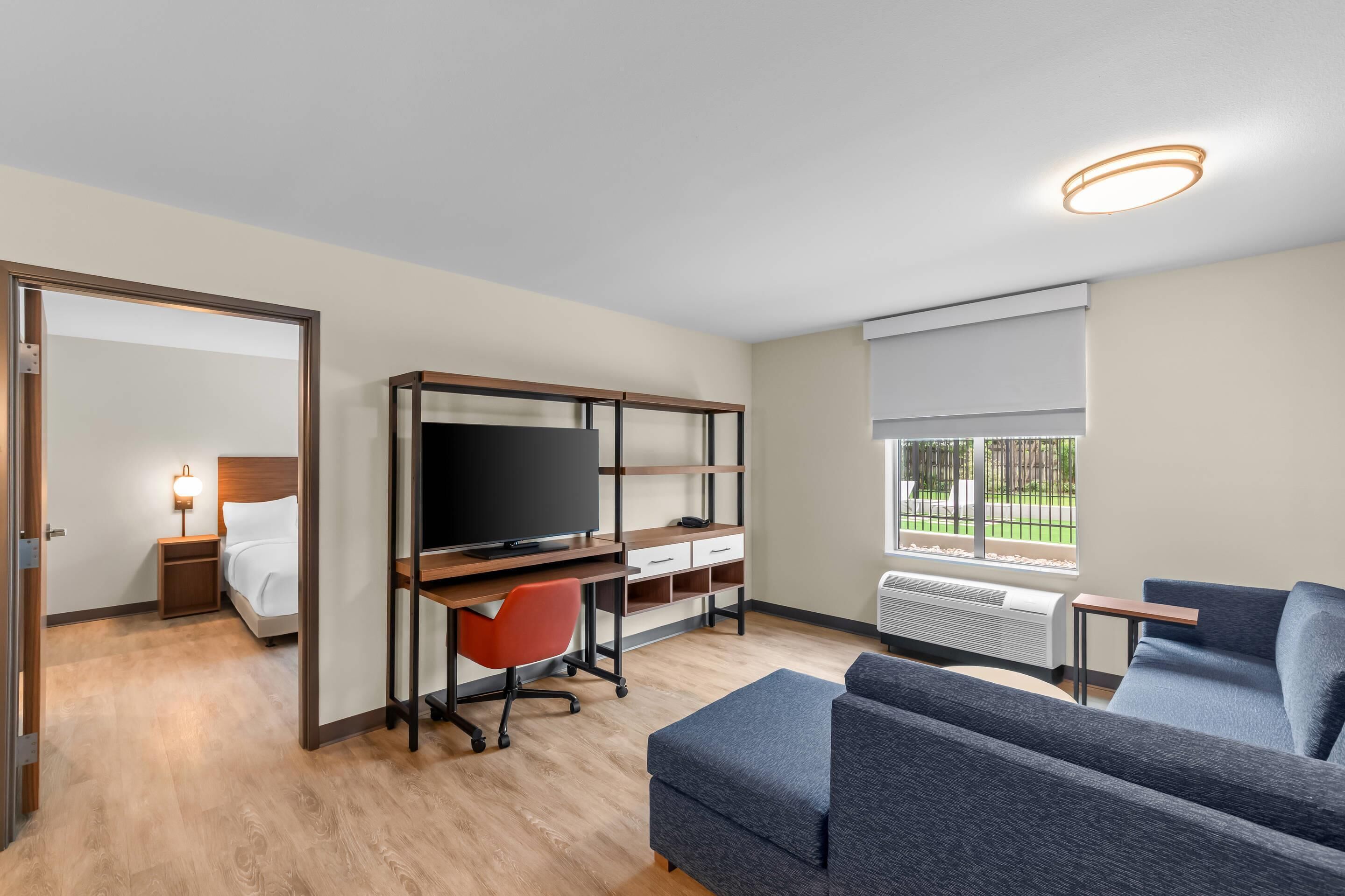 Une chambre d’hôtel moderne équipée d’un lit, d’un bureau, d’une télévision et d’un coin salon.