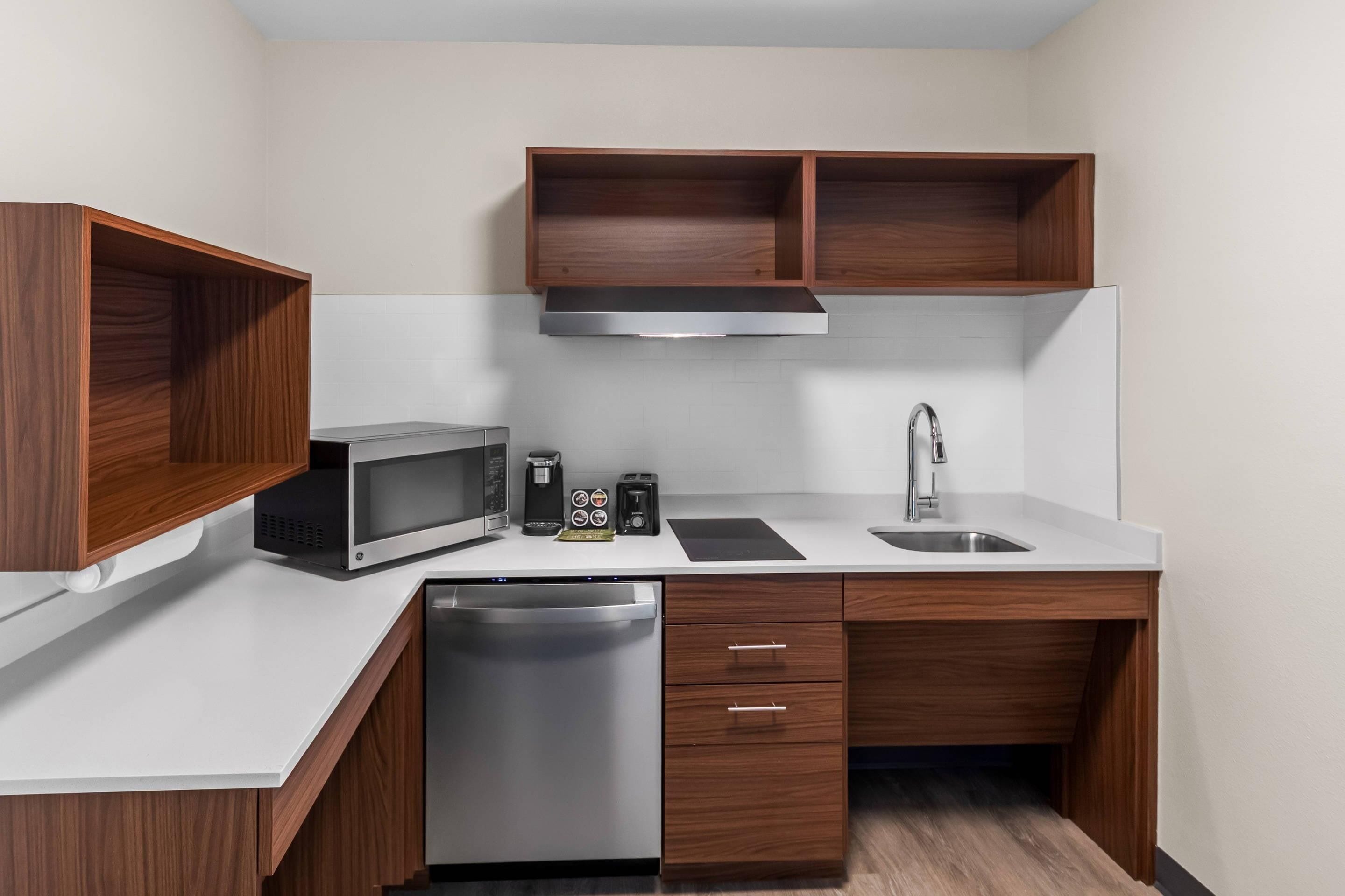 A compact kitchen with a microwave, toaster, coffee maker, sink, and dishwasher.
