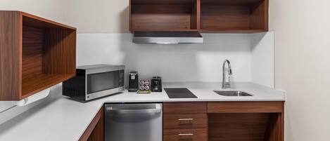 A compact kitchen with a microwave, toaster, coffee maker, sink, and dishwasher.