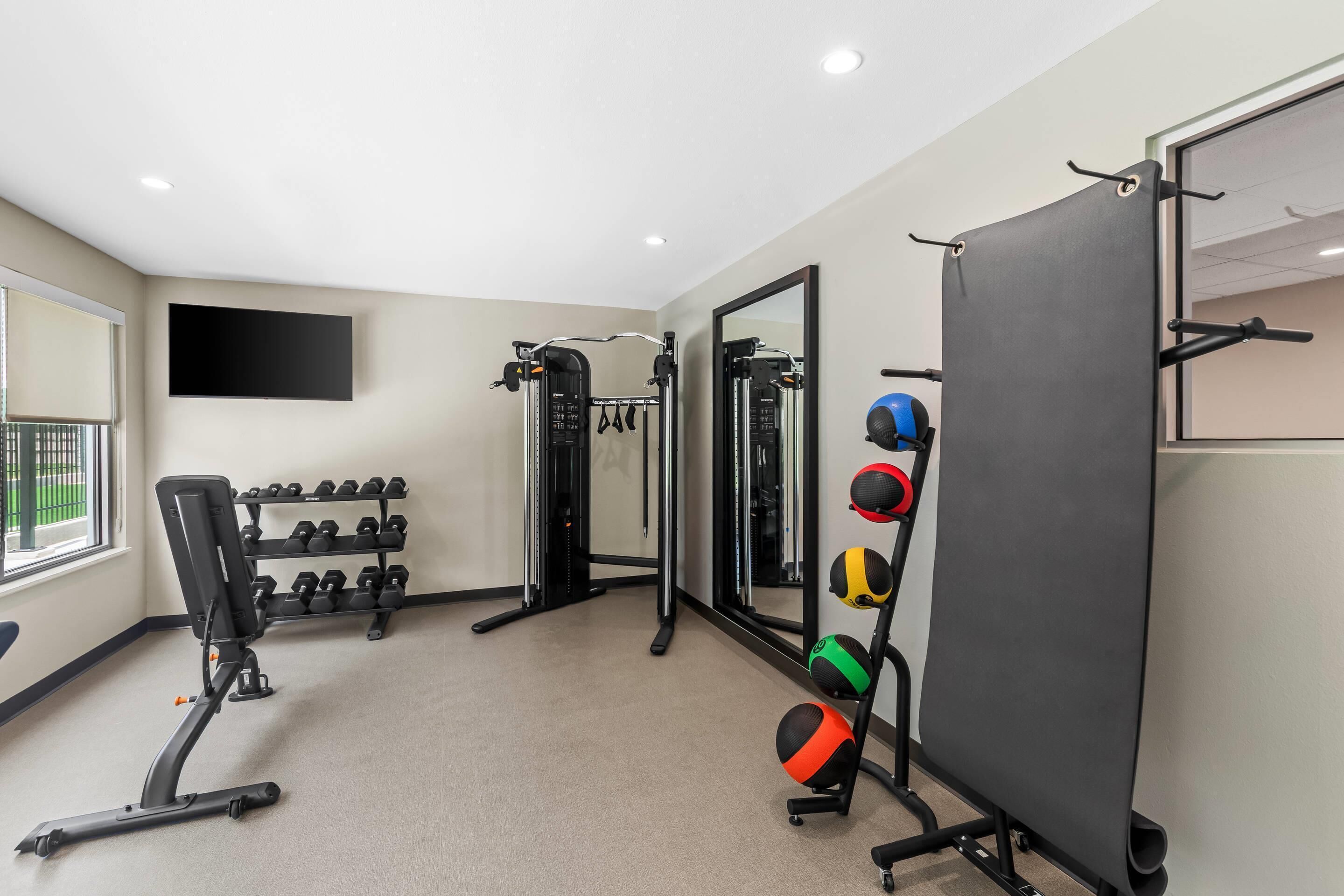 A gym with exercise equipment, a TV, and a mirror.