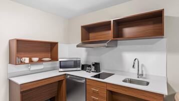 A compact kitchen with a microwave, coffee maker, and a dishwasher.