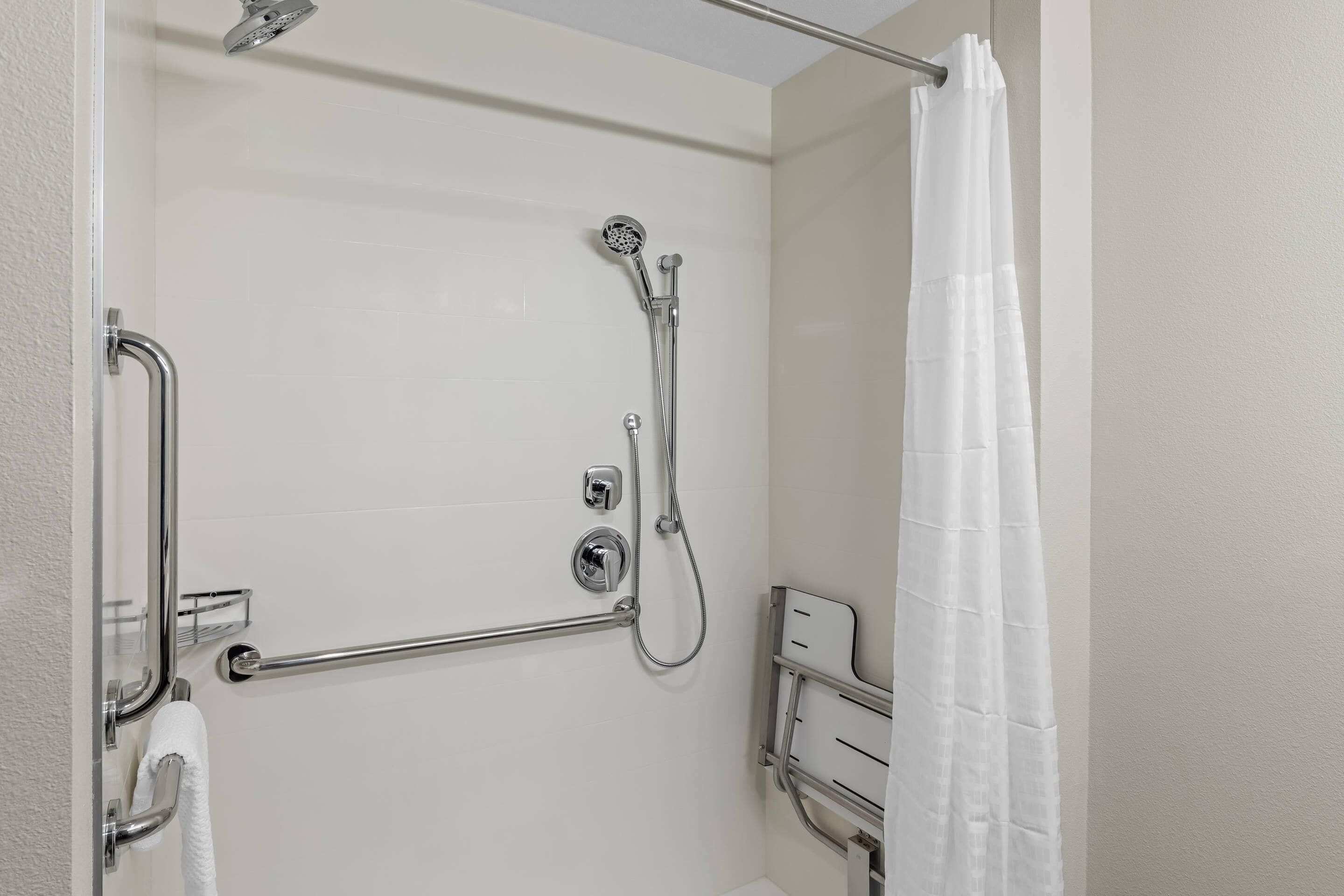 A shower with a handheld showerhead, a handheld shower attachment, and a grab bar.