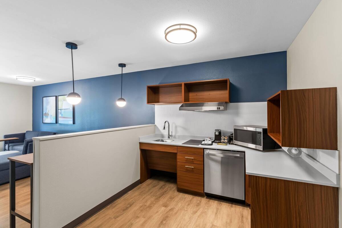 A modern kitchen with a microwave, sink, and wooden cabinets.