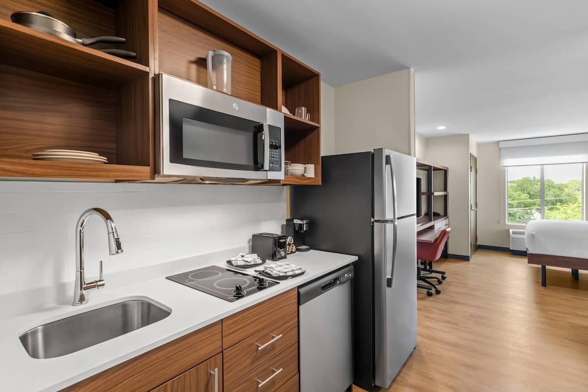 A modern kitchen with a built-in microwave, stainless steel refrigerator, and a dishwasher.