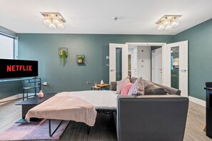 Une chambre moderne comprenant un lit, une télévision, un bureau et une porte donnant accès à une salle de bain.
