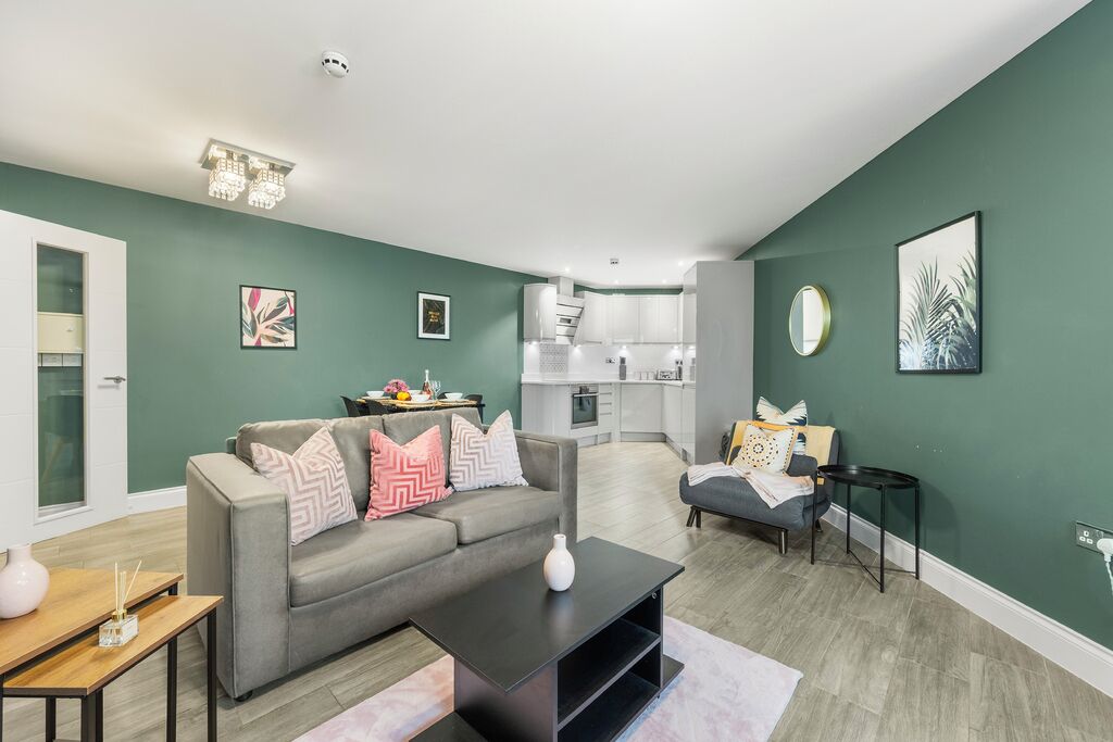 A modern living room with a grey sofa, a coffee table, and a dining area with a small table and chairs.