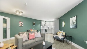 Ein modernes Wohnzimmer mit grauem Sofa, einem Couchtisch und einem Essbereich mit kleinem Tisch und Stühlen.