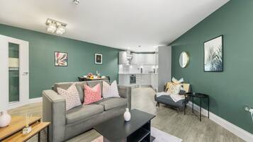 A modern living room with a grey sofa, a coffee table, and a dining area with a small table and chairs.