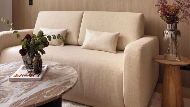 A modern living room with a beige sofa, a round coffee table, and a vase with flowers. - Elegant Apartment - AC- 2br-6p- le Marais (Paris)