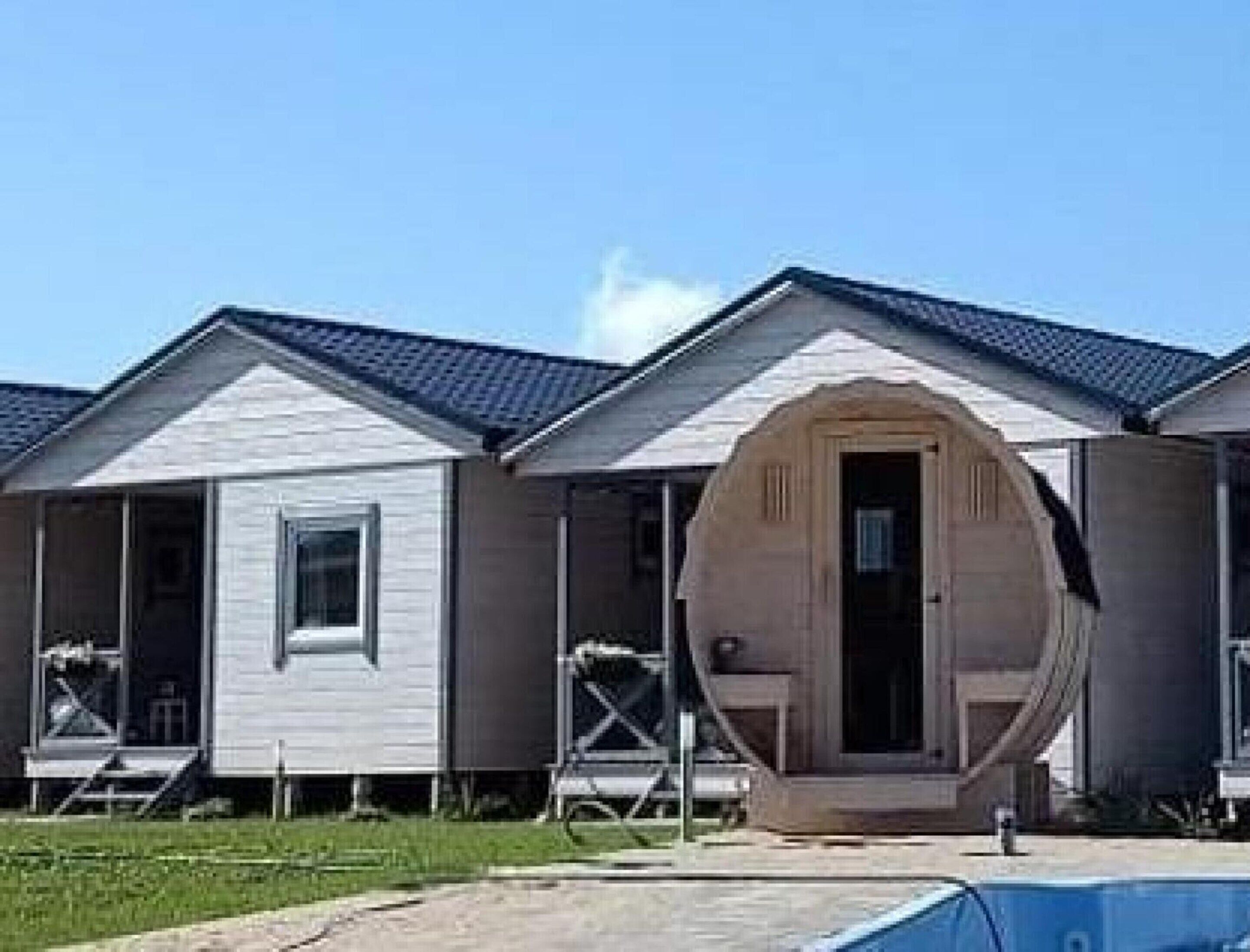 A row of single-story cabins with a simple, functional design, featuring a central door and small windows.