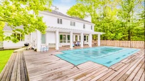 Una casa blanca con una terraza de madera y una piscina.