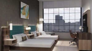 Une chambre d’hôtel moderne avec deux lits, un bureau et une grande fenêtre donnant sur la ville.