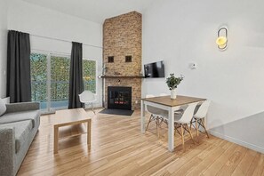 Una sala moderna con chimenea, una mesa de comedor con sillas, un sofá y un televisor instalado en la pared.