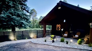 Eine rustikale Holzhütte mit einer überdachten Veranda, einem eingezäunten Hof und einem Schotterweg.