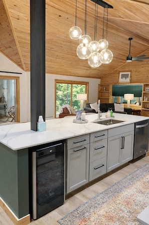 Una cocina moderna con una isla grande, electrodomésticos de acero inoxidable y techo de madera.