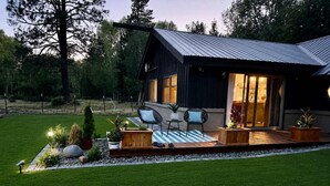 Ein modernes Haus mit Terrasse, Gartenmöbeln und einem gepflegten Rasen.