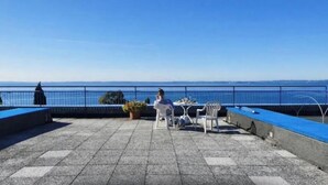A terrace with a view of the sea, a potted plant, and outdoor furniture. - Jewel on Lake Garda in Garda with Lake View (Garda)