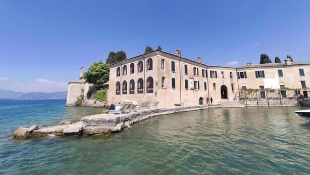 A historic building with arched windows and a stone facade, situated by a body of water. - Jewel on Lake Garda in Garda with Lake View (Garda)