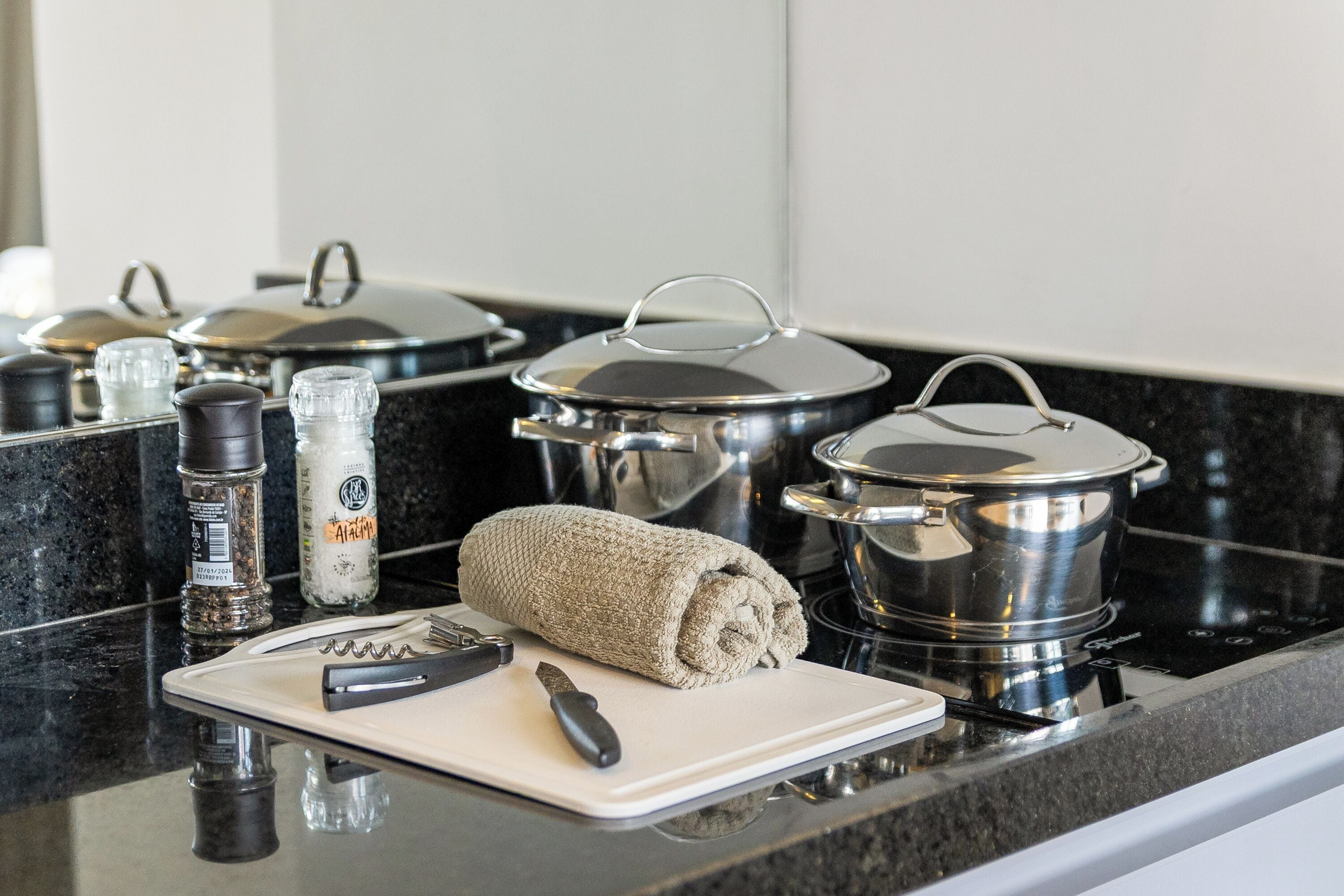 A kitchen counter with pots, a cutting board, a knife, and a salt shaker.