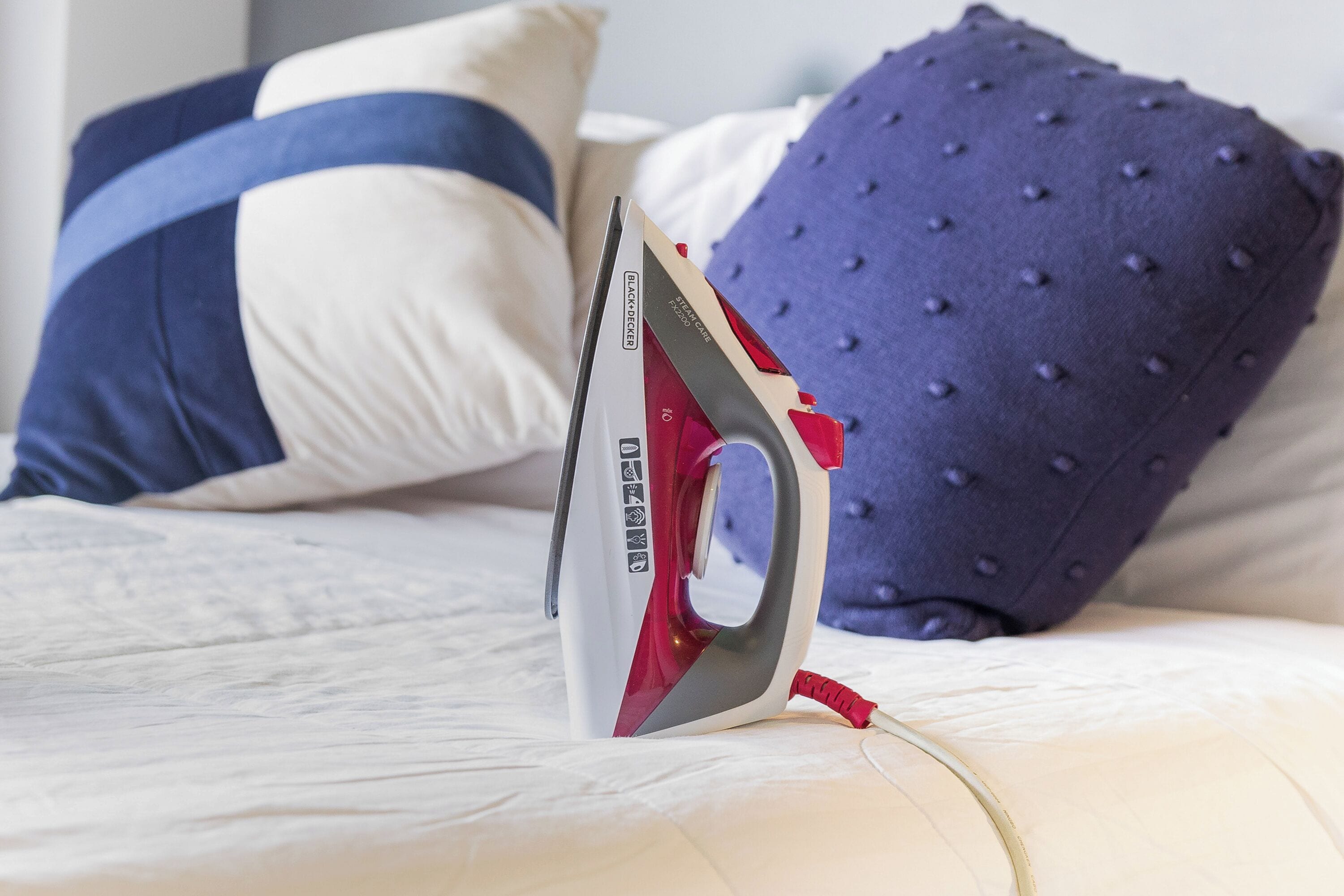 Ein Bügeleisen auf einem Bett mit Kissen.